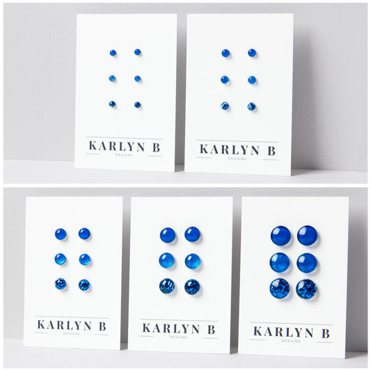 Five sets of stud earrings on white cards with the text "KARLYN B DESIGNS". Each set features three pairs of earrings in different shades of blue.
